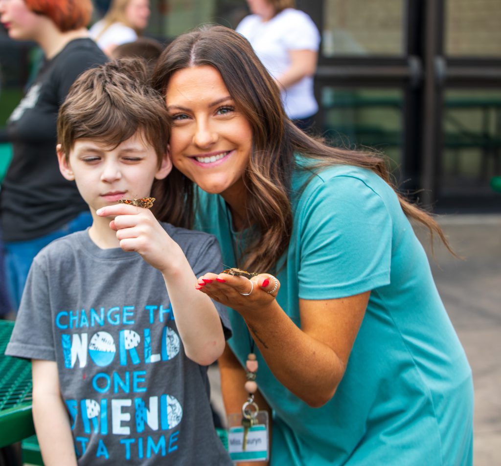 An adult and a child smile at the camera