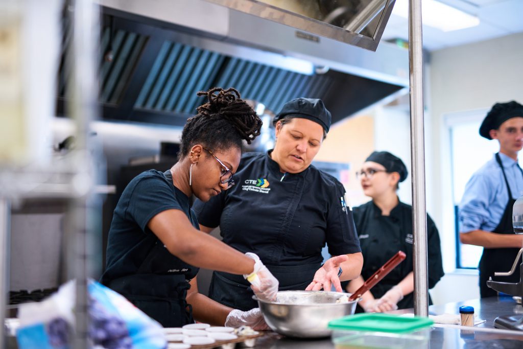 Two students prepare food in a commercial kitchen