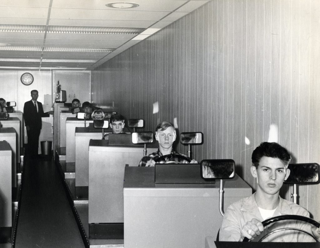 Students sit in a row at driver's education consoles