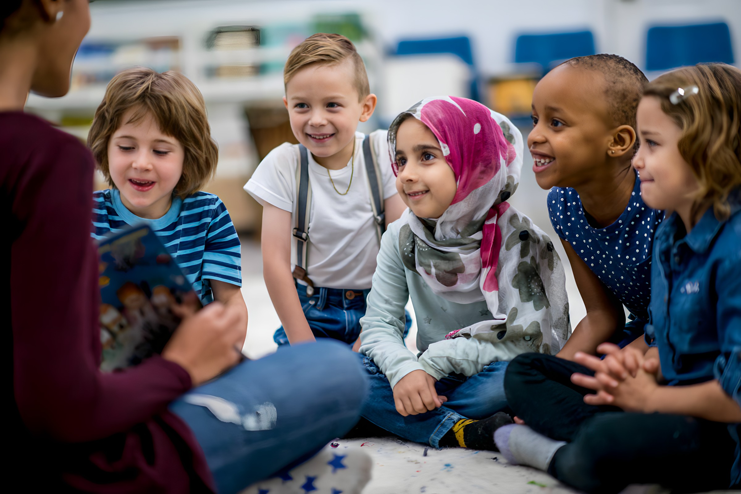 Several children are seated while an adult speaks