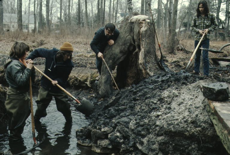 Students shoveling mud onto a stream bank.