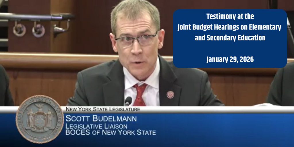 A person is facing forward sitting behind a table to speak.