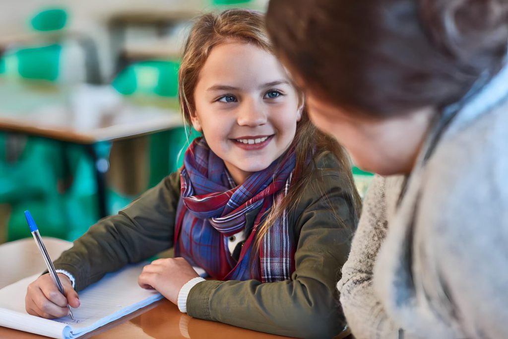 A young student smiling at their teacher.