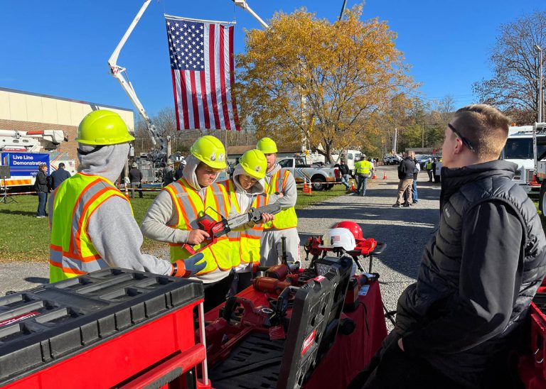 Students in safety gear looking over tools outside.