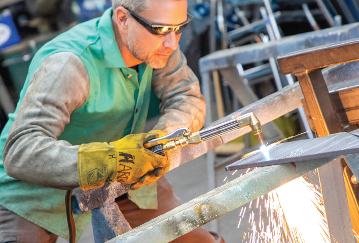 A man welding a piece of flat steel.