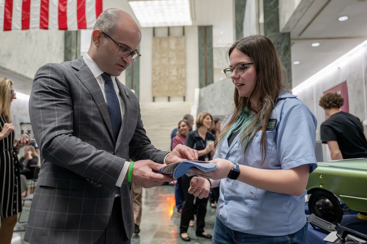 A female student and male state senator hold a textile in the Well of the Legislative Office Building in Albany