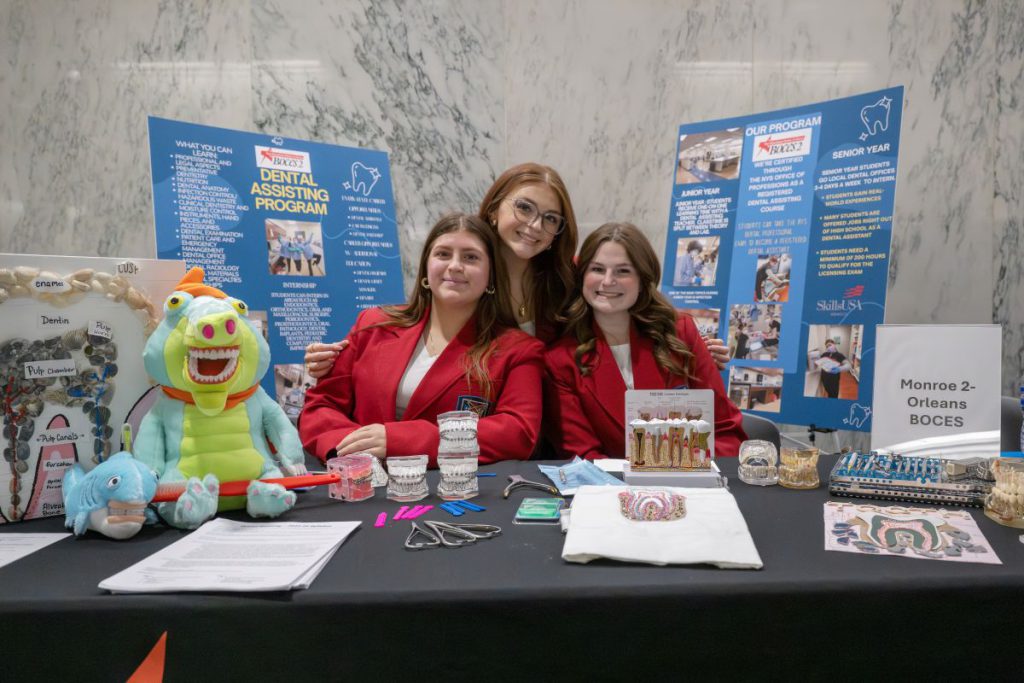 Three dental assisting students from Monroe 2 Orleans BOCES pose with their tooth models and display